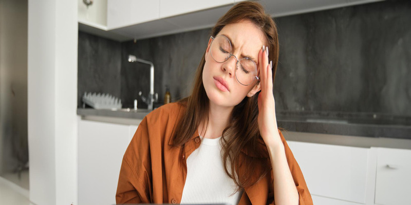 A woman working with a headache. Headaches may be a result of indoor air quality issues.