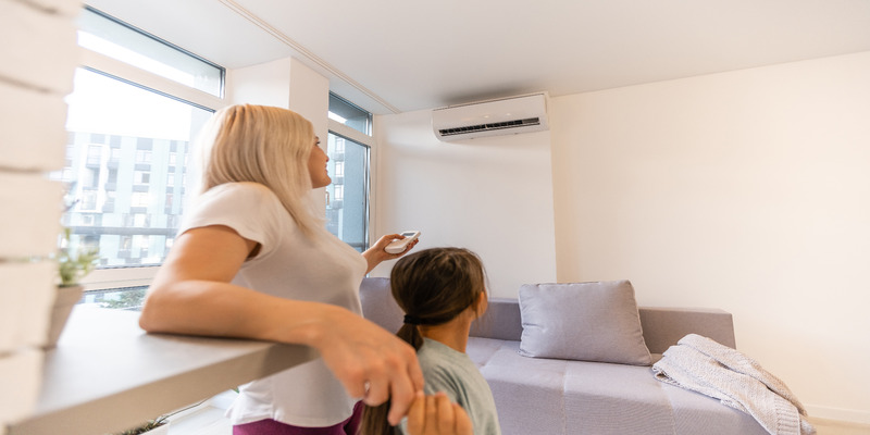 A woman turns on the fan mode on her air conditioner.