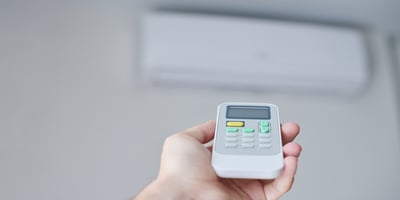 A man holds an air conditioner remote control.