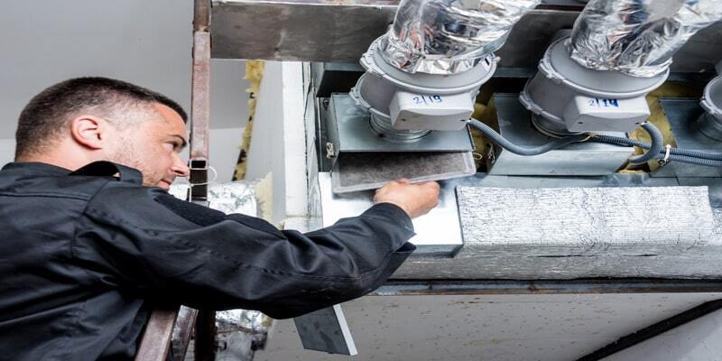 A man is replacing the filters that the air conditioning system uses.