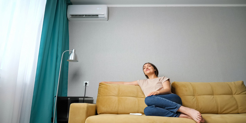 Woman relaxing in a cooled room, staying cool in summer with air conditioning.