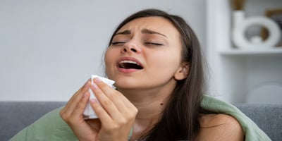 Woman about to sneeze indoors, showing allergy signs in Air Conditioning