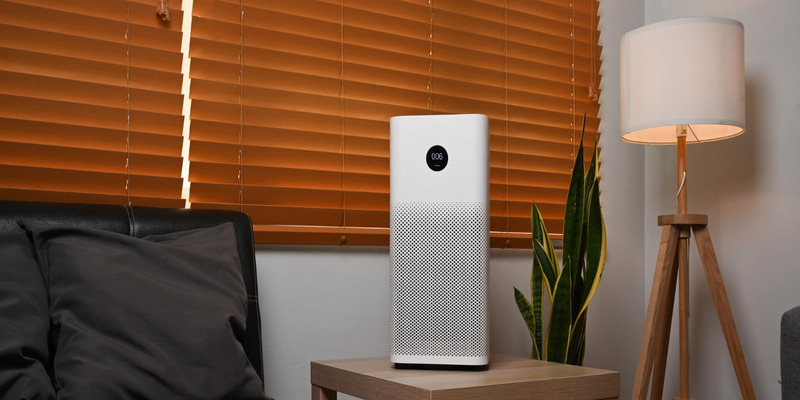 Tall white air purifier on a side table in a warm, modern room