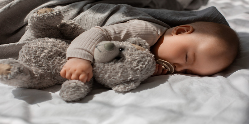 Baby sleeping with teddy bear in cozy room
