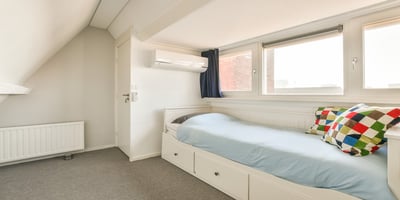 Room with bed and a dorm room air conditioner for comfort.