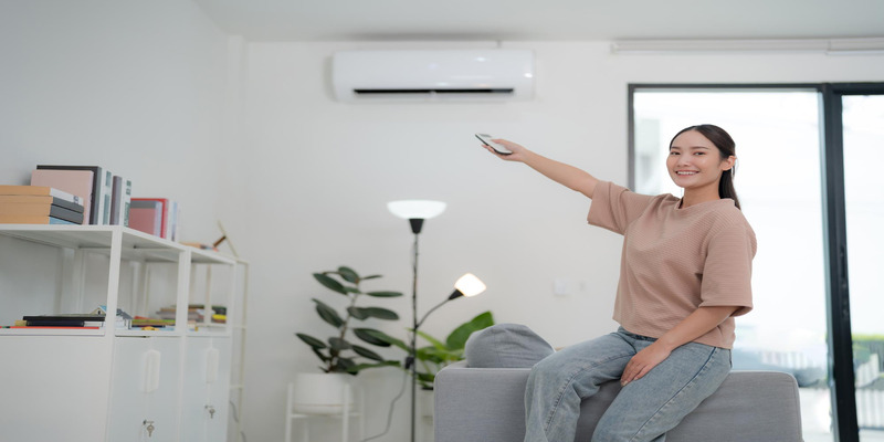 Woman controlling wall mounted air conditioner with remote