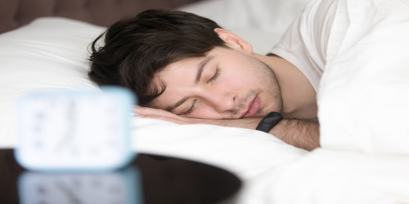 Man sleeping in bed with air quality monitor nearby