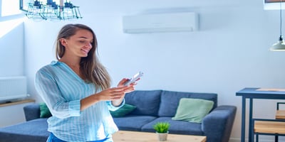 Woman holding air conditioner remote control